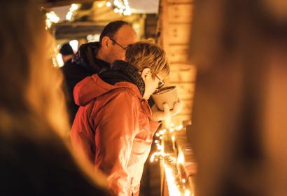 Une dame sent une bougie sur le marché de Noël des Jardins d'Annevoie