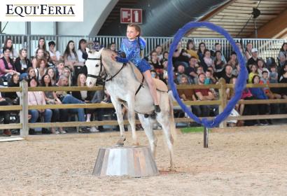 Petite fille sur un cheval blanc lors d'une représentation équestre 